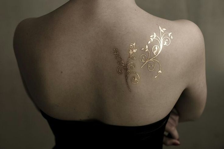 the back of a woman's shoulder with tattoos on it