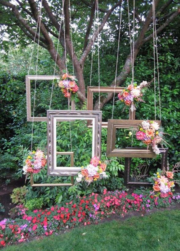 four frames hanging from a tree with flowers in the foreground and another frame on the other side