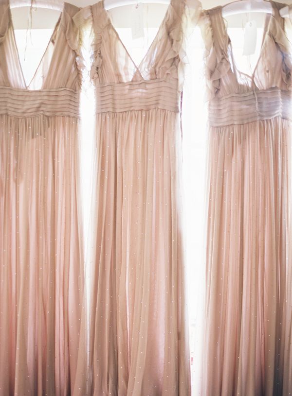 four bridesmaid dresses hanging in front of a window