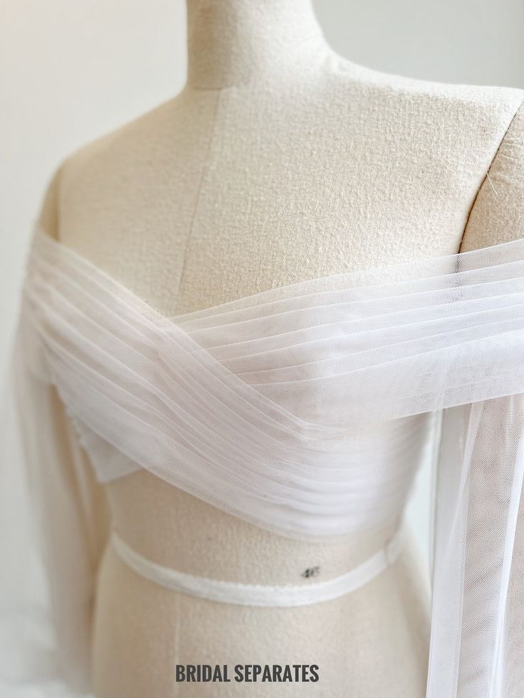 the back of a white wedding dress on a mannequin headdress with sheer tulle