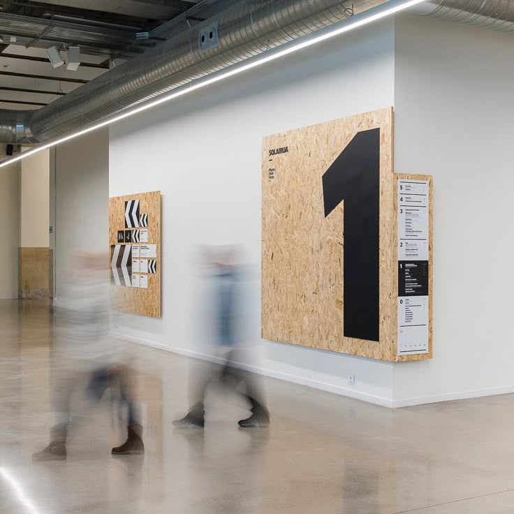 blurry photograph of people walking in an open space with posters on the wall and floor