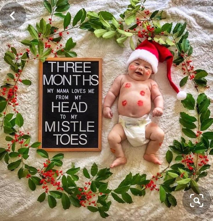 a baby laying on top of a bed next to a sign