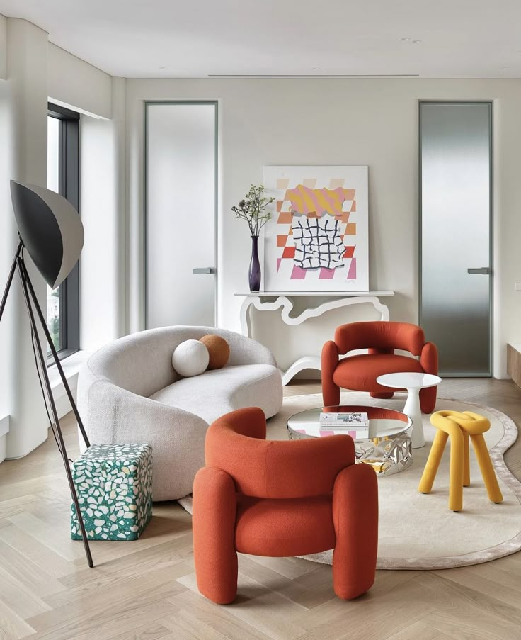 a living room filled with lots of different colored furniture and decorating items on top of hard wood flooring