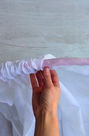 someone is holding the end of a white piece of paper with pink tape on it