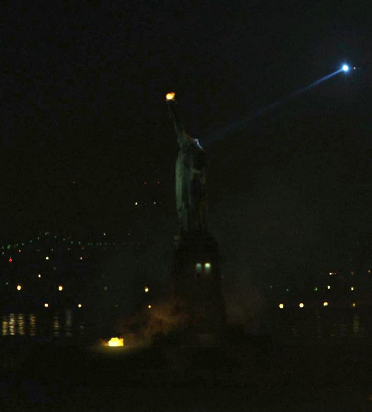 the statue of liberty is lit up at night with its lights on and in the dark