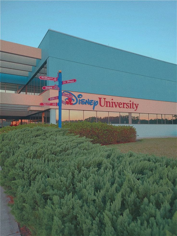 a building with a sign that says disney university in front of it and some bushes