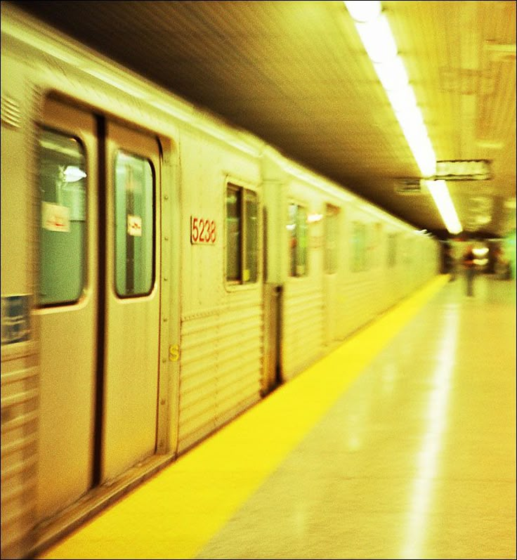 a subway train with its doors open and people walking on the platform next to it