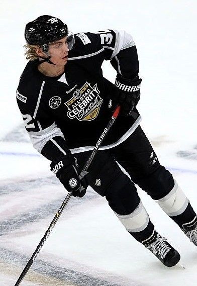 a man in black and white uniform on skis going down the ice with poles