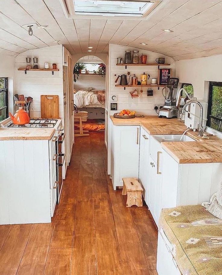 the inside of a tiny home with wood floors and white walls, open kitchen area