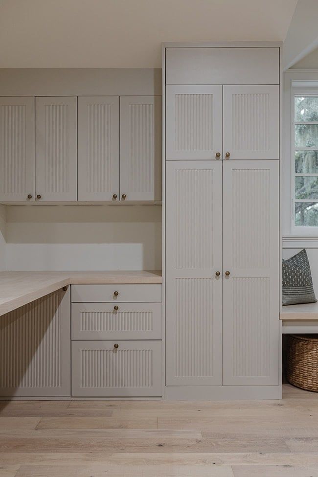 an empty kitchen with white cabinets and wood flooring