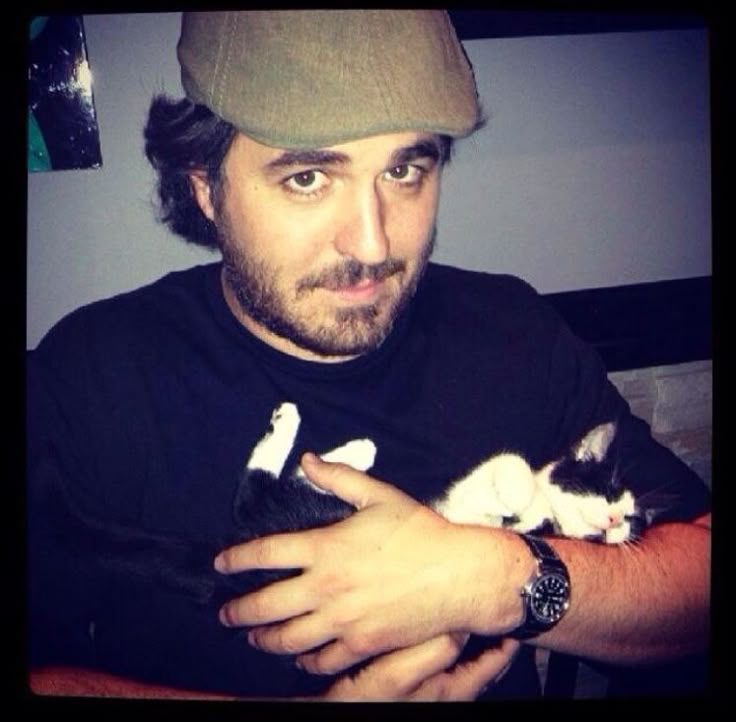 a man holding a black and white kitten