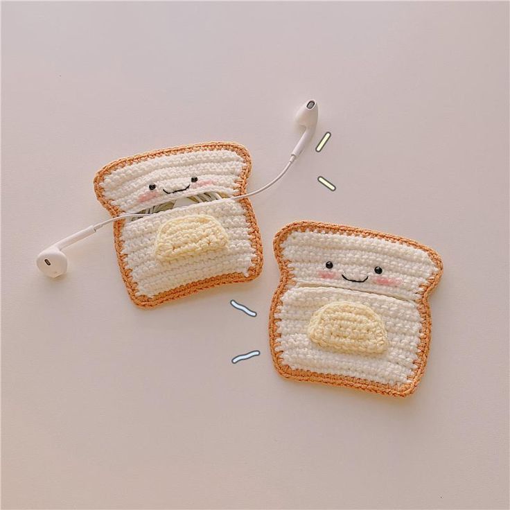 two pieces of toast with faces made out of crocheted material, one is white and the other is orange