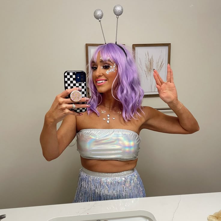 a woman with purple hair is taking a selfie in front of a mirror and holding a cell phone