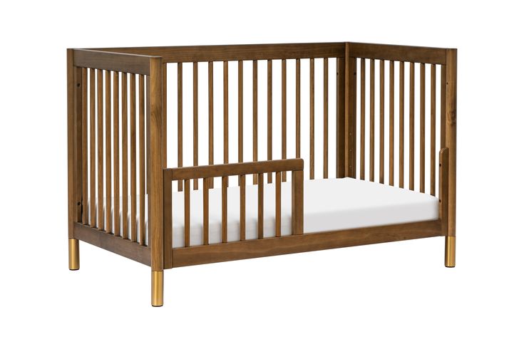 a wooden crib with white sheets on the bottom and side rails, against a white background