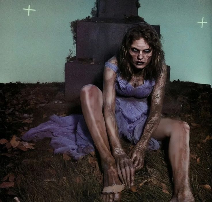 a woman sitting on the ground in front of a grave with blood all over her body