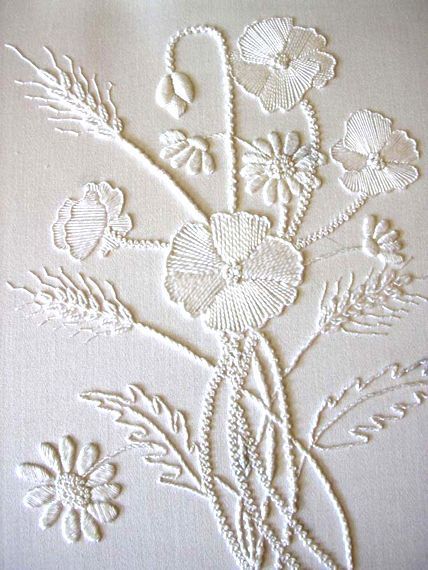 a white table cloth with flowers and leaves on it's side, embroidered onto the fabric