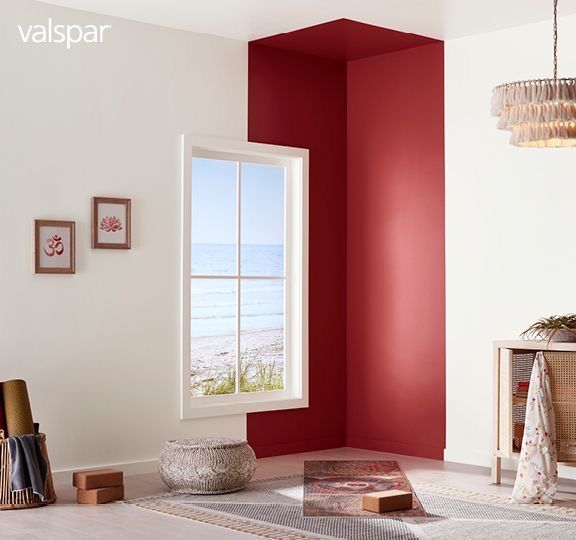 a living room with red walls and white carpeted flooring next to an open window