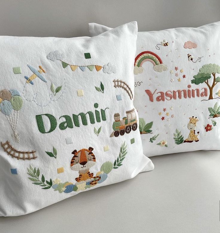 two white pillows with animals and letters on them