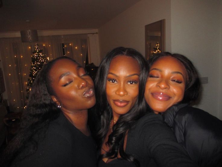 three beautiful women posing for the camera in front of a christmas tree with lights behind them