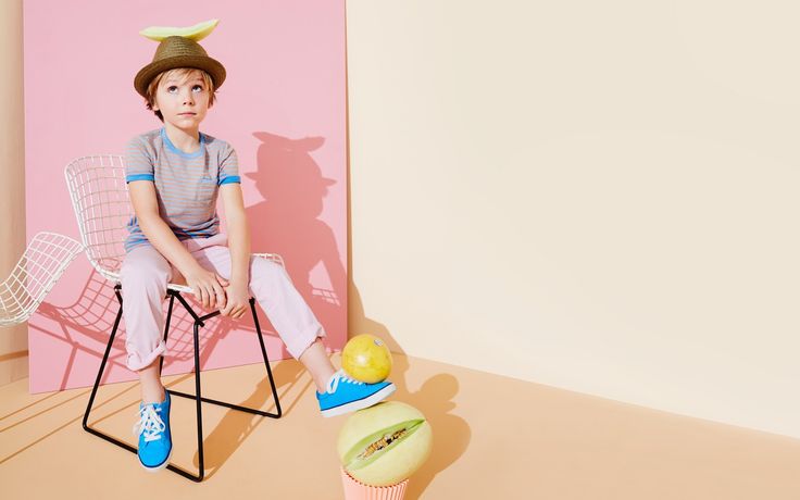 a young boy sitting on top of a chair next to a cupcake and banana