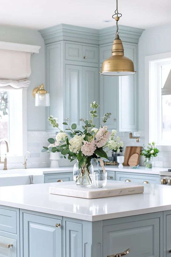 a kitchen island with flowers in a vase on the top and an overhead light hanging over it