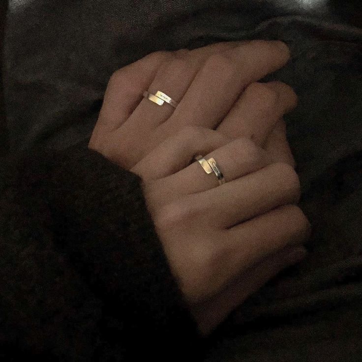 two women's hands with gold rings on their fingers, both holding each other