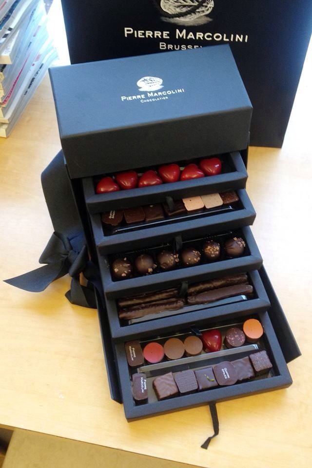 an assortment of chocolates sitting on top of a wooden table next to a black box