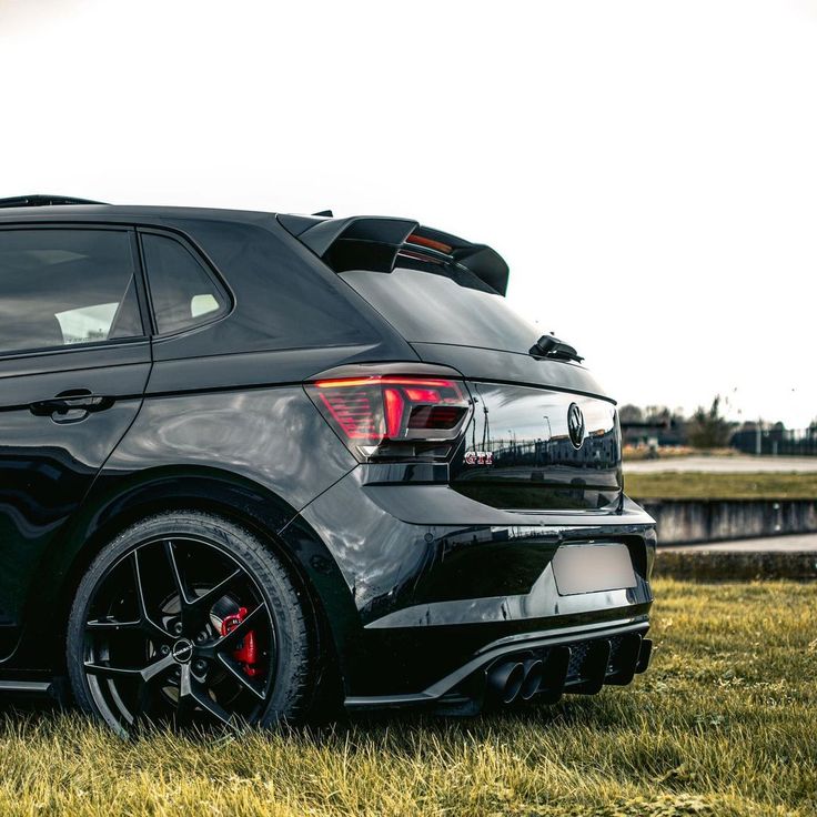 the rear end of a black car parked on grass