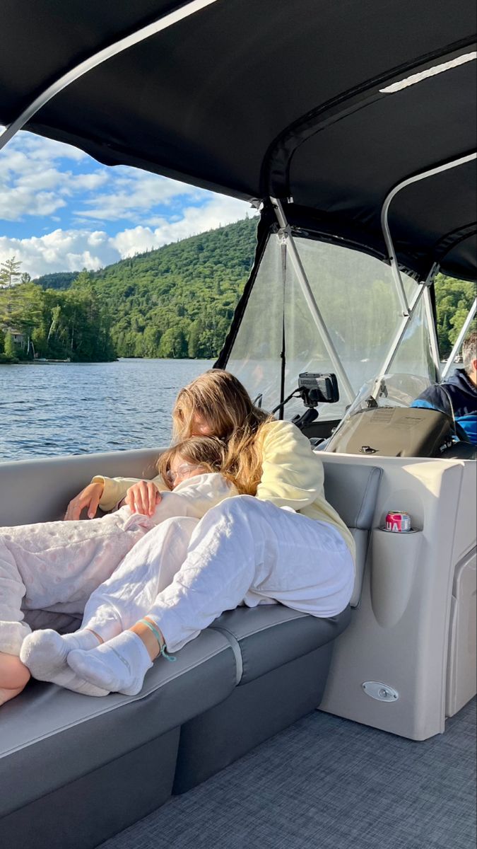 two women sitting on the back of a boat with their arms around each other as they relax