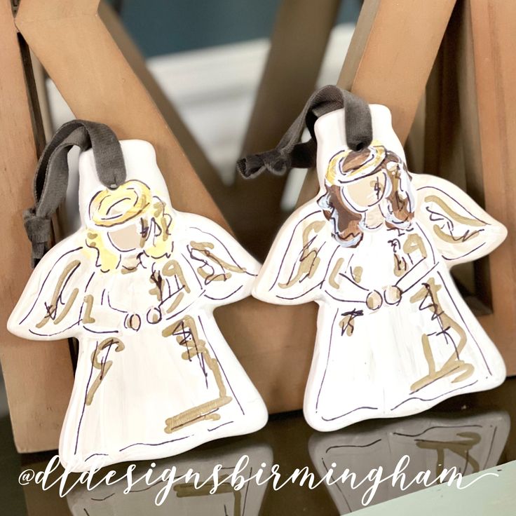 two angel figurines sitting on top of a wooden chair next to each other