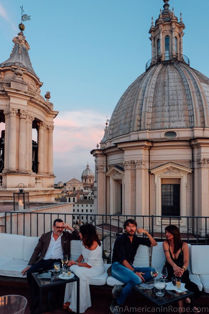 several people sitting on white couches in front of an old building with dome tops