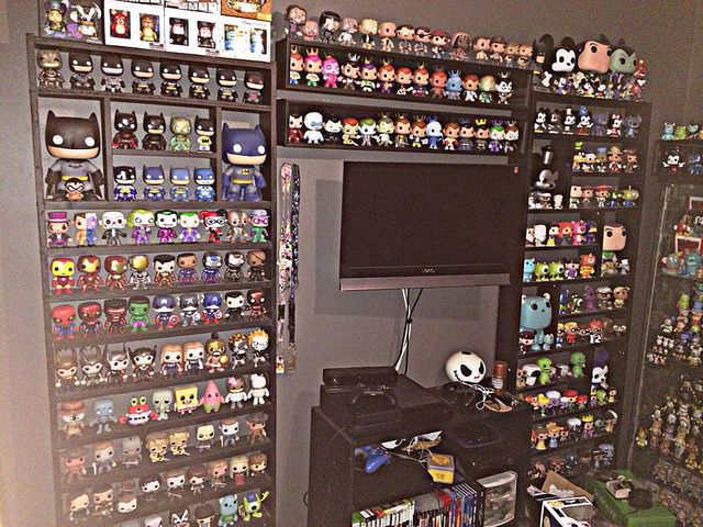 a room filled with lots of different types of action figures on shelves next to a flat screen tv