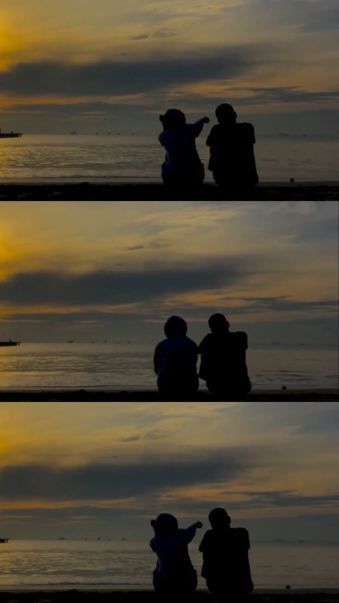 two people sitting on the beach at sunset