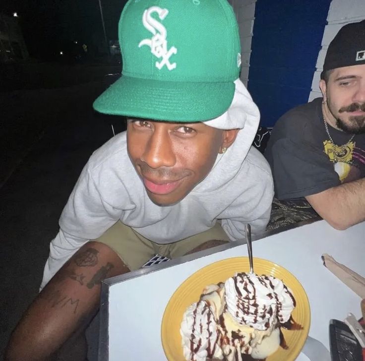 a man with a green hat is looking at a plate of ice cream sundaes