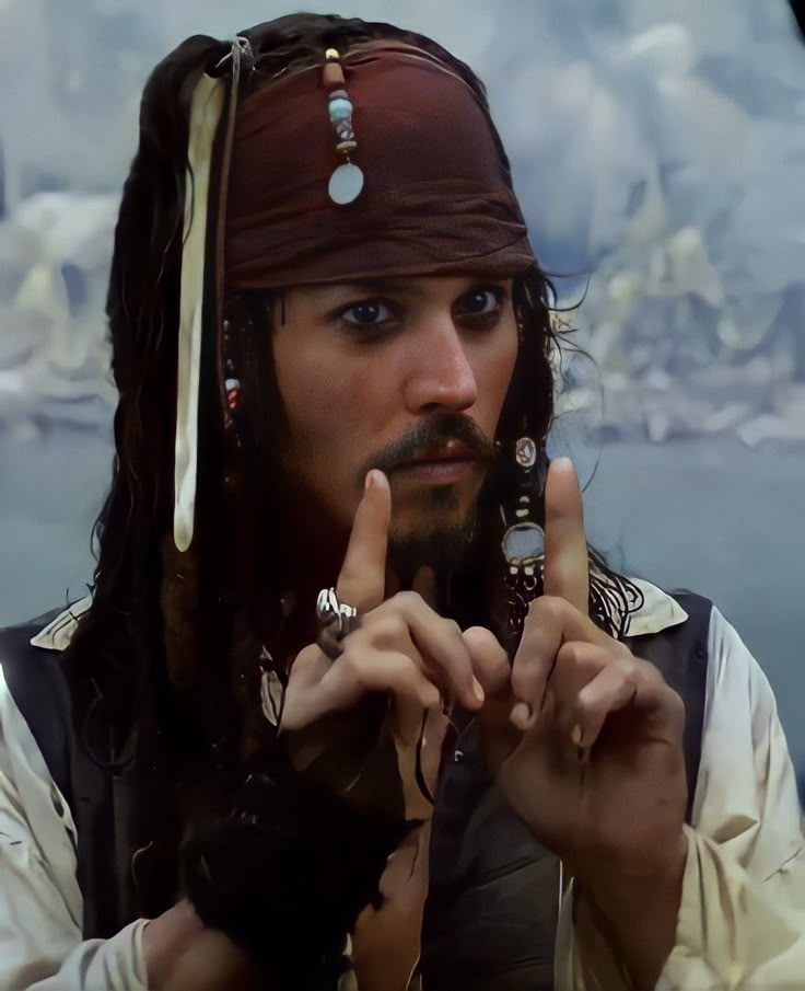 a man dressed as captain jack sparrow holding two fingers up to the side with one hand