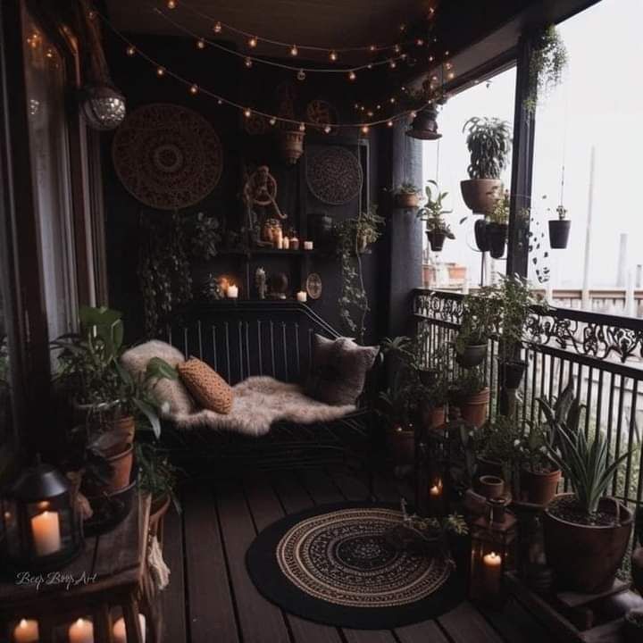 a balcony with potted plants and candles on the floor, along with lights strung from the ceiling