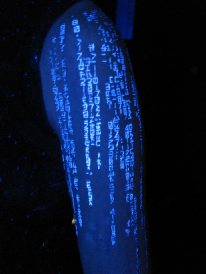 the back of a person's arm with writing projected on it in blue light