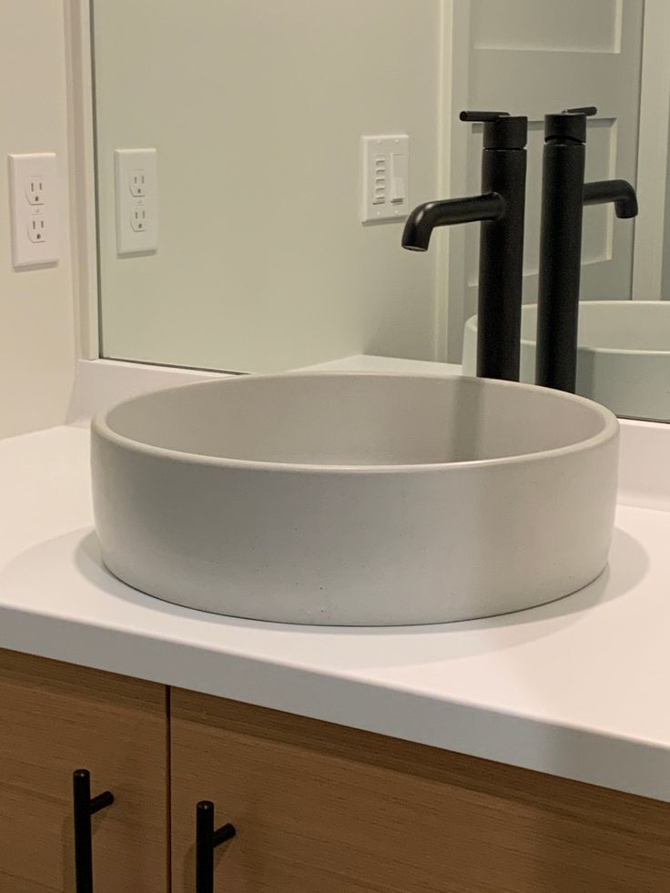 a white bowl sink sitting on top of a counter in front of a bathroom mirror