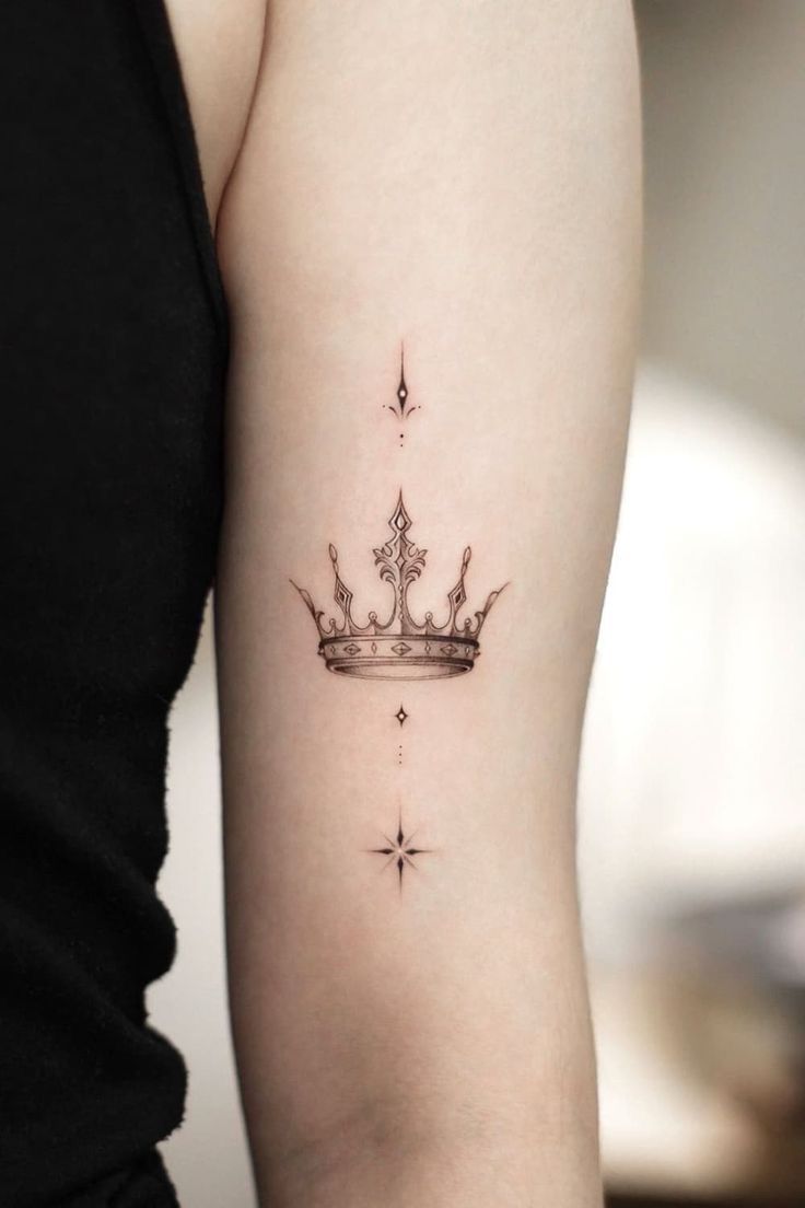 a woman's arm with a crown tattoo on the left side of her arm