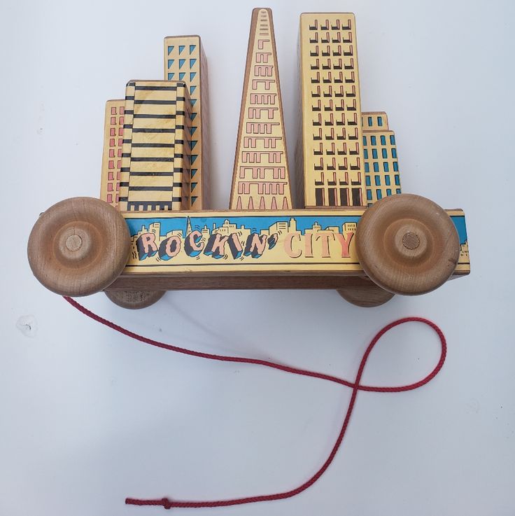 a wooden toy car with wheels and tires on the front that is attached to a red string