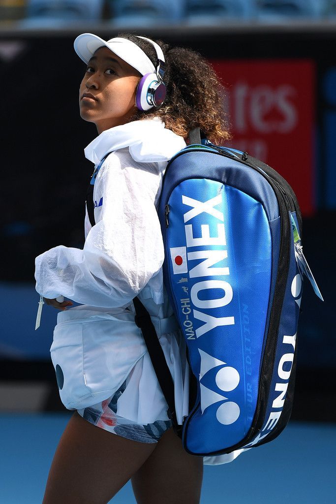 a female tennis player in action on the court with her back pack and headphones