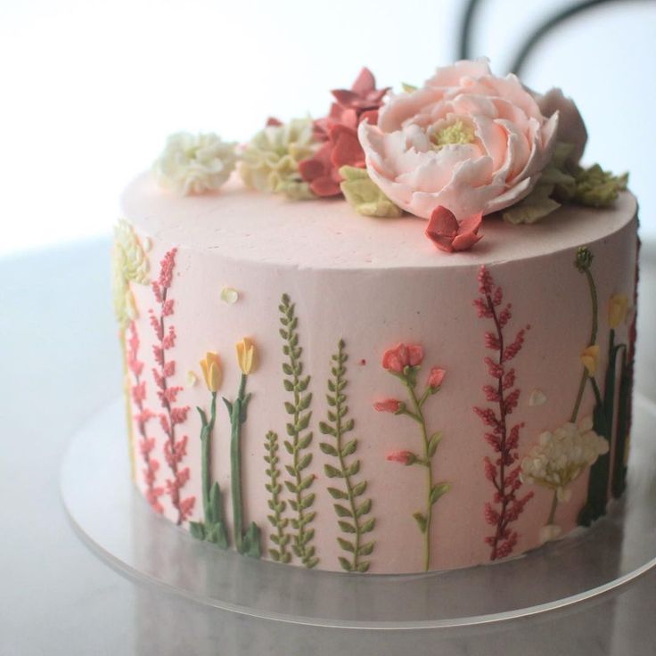 a pink cake decorated with flowers and leaves