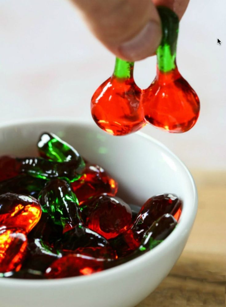 a bowl filled with jelly candy sitting on top of a wooden table next to a spoon