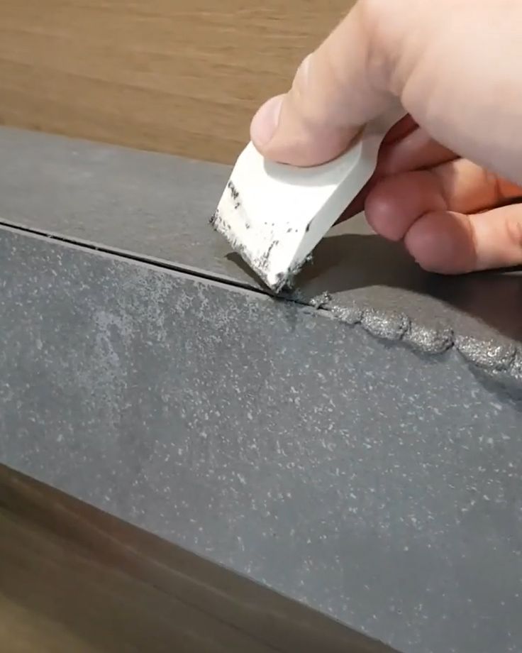 a person using a brush to paint the edge of a piece of wood with cement