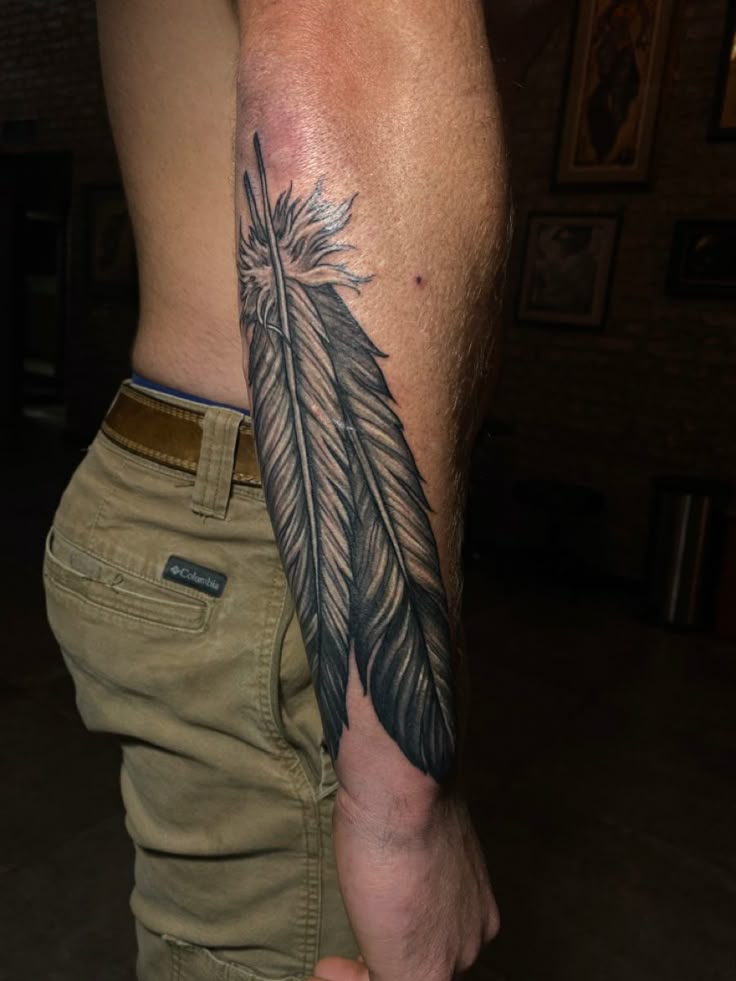 a man with a feather tattoo on his arm