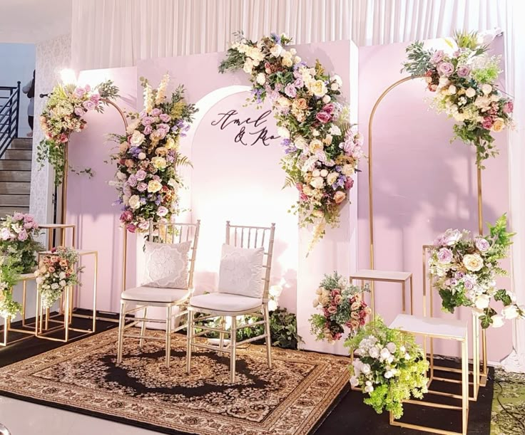 a wedding ceremony setup with chairs and flowers on the back wall, in front of a floral backdrop