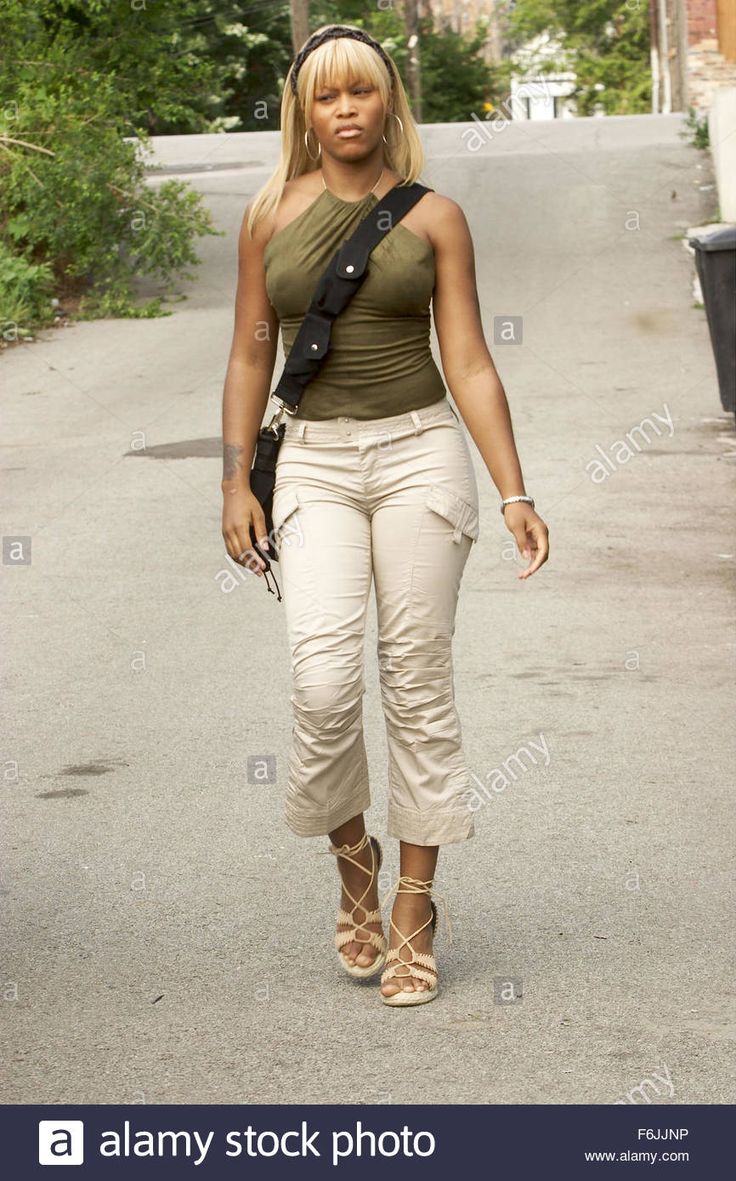 a woman walking down the street with her hand on her hip, looking back at the camera