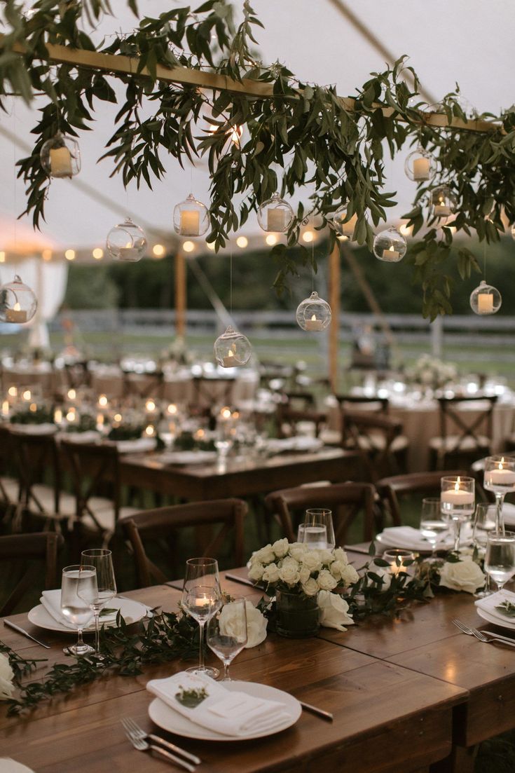 the tables are set with white flowers and greenery for an elegant wedding reception in a tent