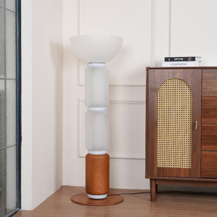 a white lamp sitting on top of a wooden floor next to a cabinet and door