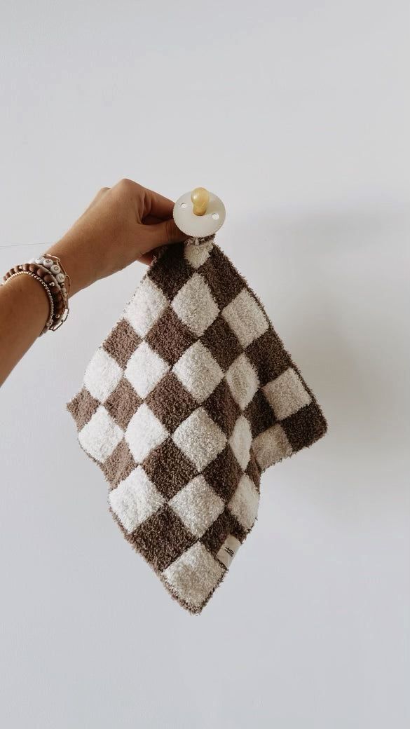 a hand holding a brown and white checkered towel